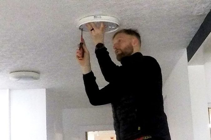 KF Watson engineer working from a ladder installing ceiling lighting in an office